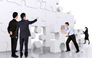 A group of business people standing around a puzzle piece.