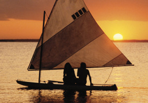 Two people on a sailboat at sunset.