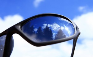 A pair of sunglasses reflected in a blue sky.