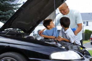 A man and two children are working on a car.