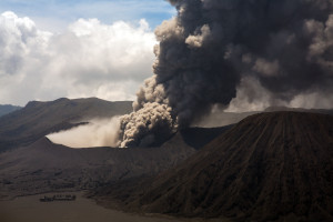 A black smoke billows from a volcano in indonesia.