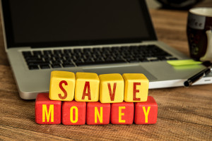 A laptop with the word save money spelled out on a wooden table.