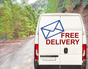 A white van driving down a road with the word free delivery on it.