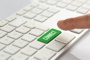 A person pressing a green button on a white keyboard.