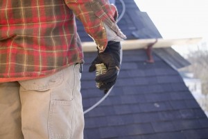 A man in a plaid shirt is standing on top of a roof.