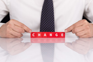 A businessman holding a block with the word change on it.