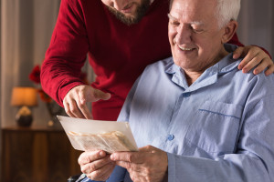 A man in a wheelchair is reading a letter to an elderly man.