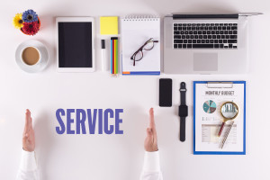 The word service on a desk with a laptop and a phone.