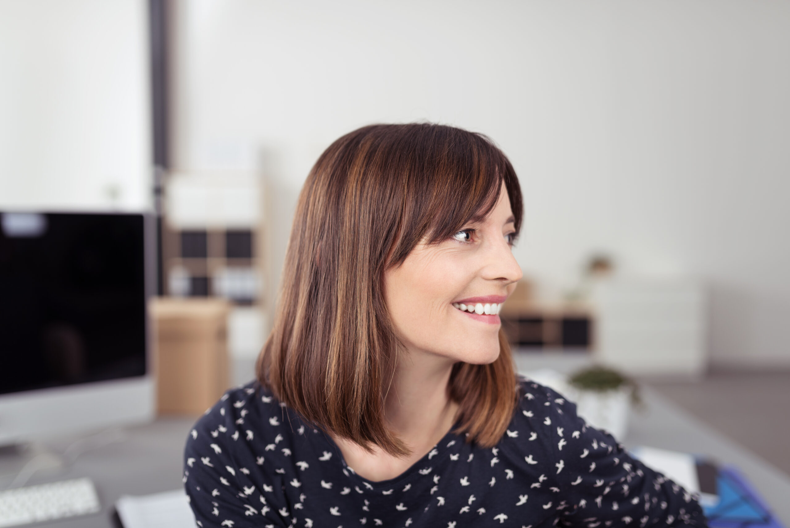 A smiling woman sitting at her desk in an office.