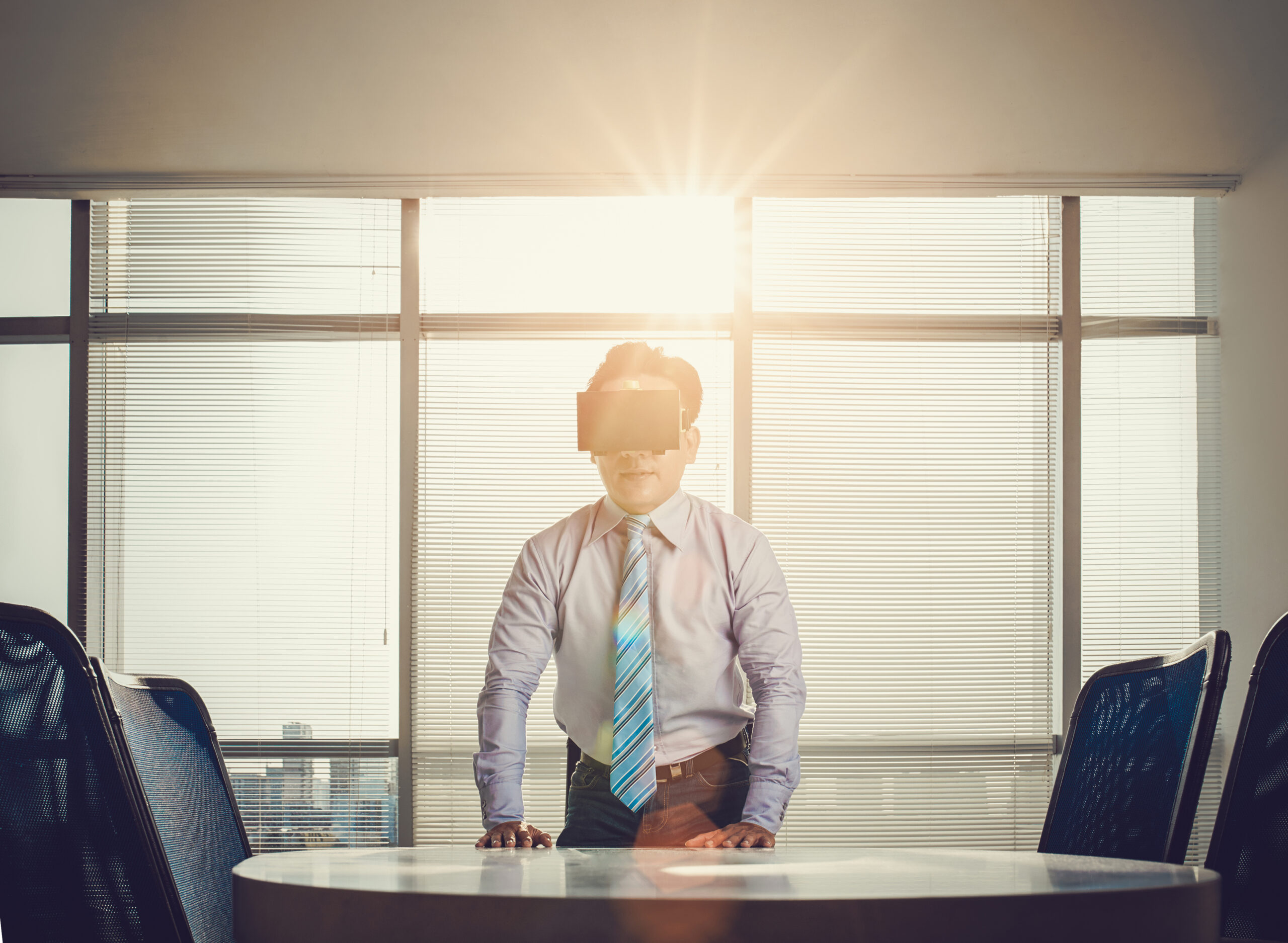 A businessman wearing a virtual reality headset at a conference table.