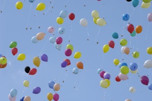 A bunch of balloons flying in the sky.