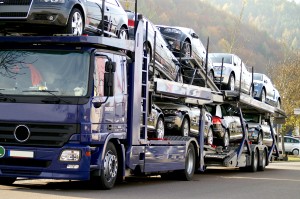 A blue truck with a load of cars on it.