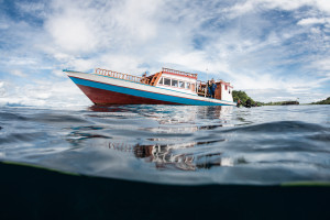 A boat is floating in the water near a cloudy sky.