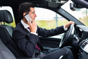 A man in a suit is talking on his cell phone in a car.