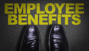 A person's feet standing on a black floor with the word employee benefits written on it.