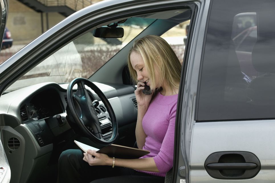 A woman talking on a cell phone in a car.