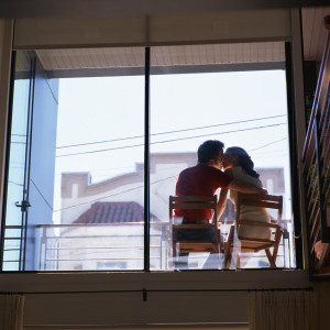 A couple sitting on chairs in front of a window.