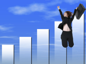 A business woman jumping over a bar graph.