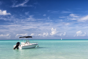 A small boat is floating in the clear blue water of the caribbean.