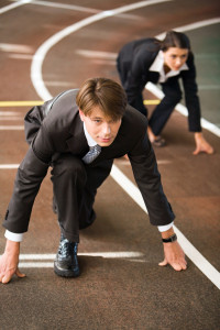 Two business people crouching on a track.