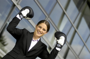 A business woman with boxing gloves in front of a building.