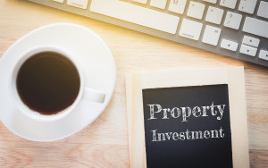 A cup of coffee next to a chalkboard with the word property investment.