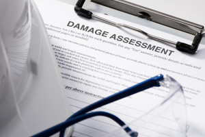 A damage assessment document on top of a hard hat and glasses.