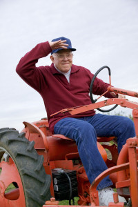 An older man sitting on a tractor.