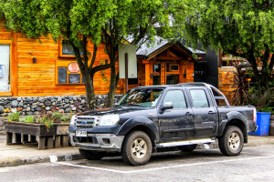 A black pickup truck parked in front of a wooden building.