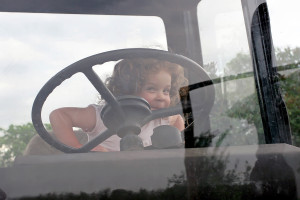 A little girl sitting in the driver's seat of a tractor.