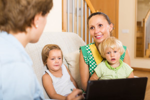 A woman and her children are sitting on a couch with a laptop.