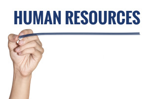 A hand holding a marker with the word human resources written on it.