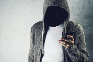 A man in a hoodie holding a cell phone.