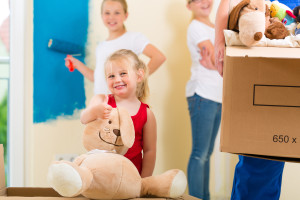 A young girl holding a teddy bear in a moving box.