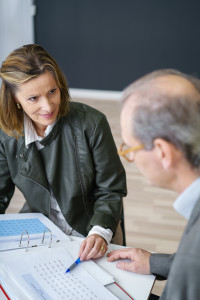 A woman and a man talking at a desk.