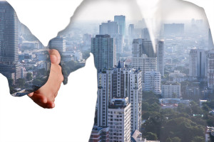 Two businessmen shaking hands in front of a city.