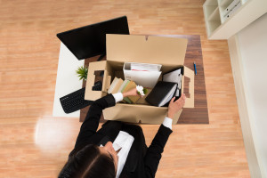 A woman in a business suit is opening a box in her office.