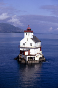 A lighthouse on an island in the middle of the ocean.