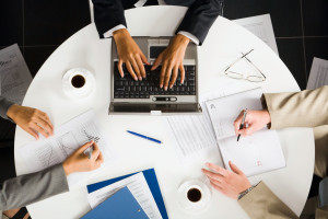 A group of business people working on a laptop at a table.