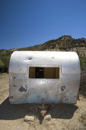 An old silver camper sits in the desert.