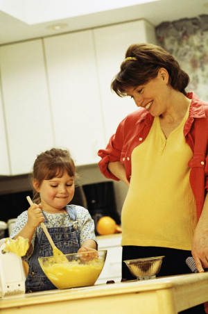 A pregnant woman and a little girl in a kitchen.