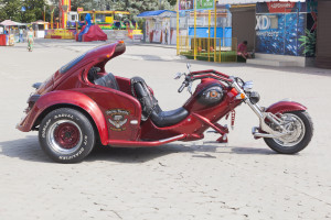 A red motorcycle with a sidecar parked in a parking lot.