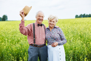 An older couple standing in a field of yellow flowers.