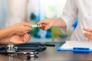 A doctor is giving a pill to a patient.