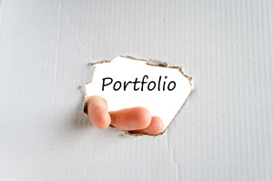 A hand reaching through a hole in a piece of paper with the word portfolio.