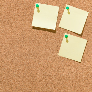 Three yellow sticky notes on a corkboard.