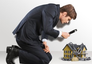 A businessman looking at a house chained to a chain.