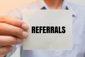 A man holding up a piece of paper with the word referrals on it.