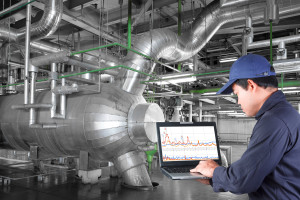 A man using a laptop in a factory.