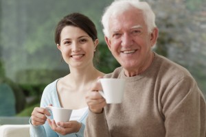 A woman and an older man holding coffee mugs.